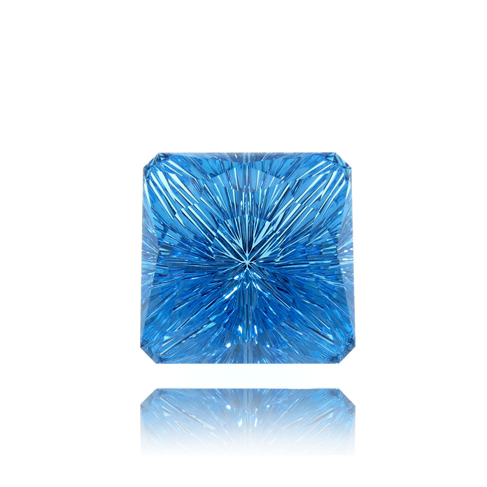 This gorgeous 25.92ct square cut gem is by award-winning gem cutter John Dyer. Cut in his signature starburst faceted cut, this teal-colored Blue Topaz is a real stunner. Item #CCJ-BT-602.